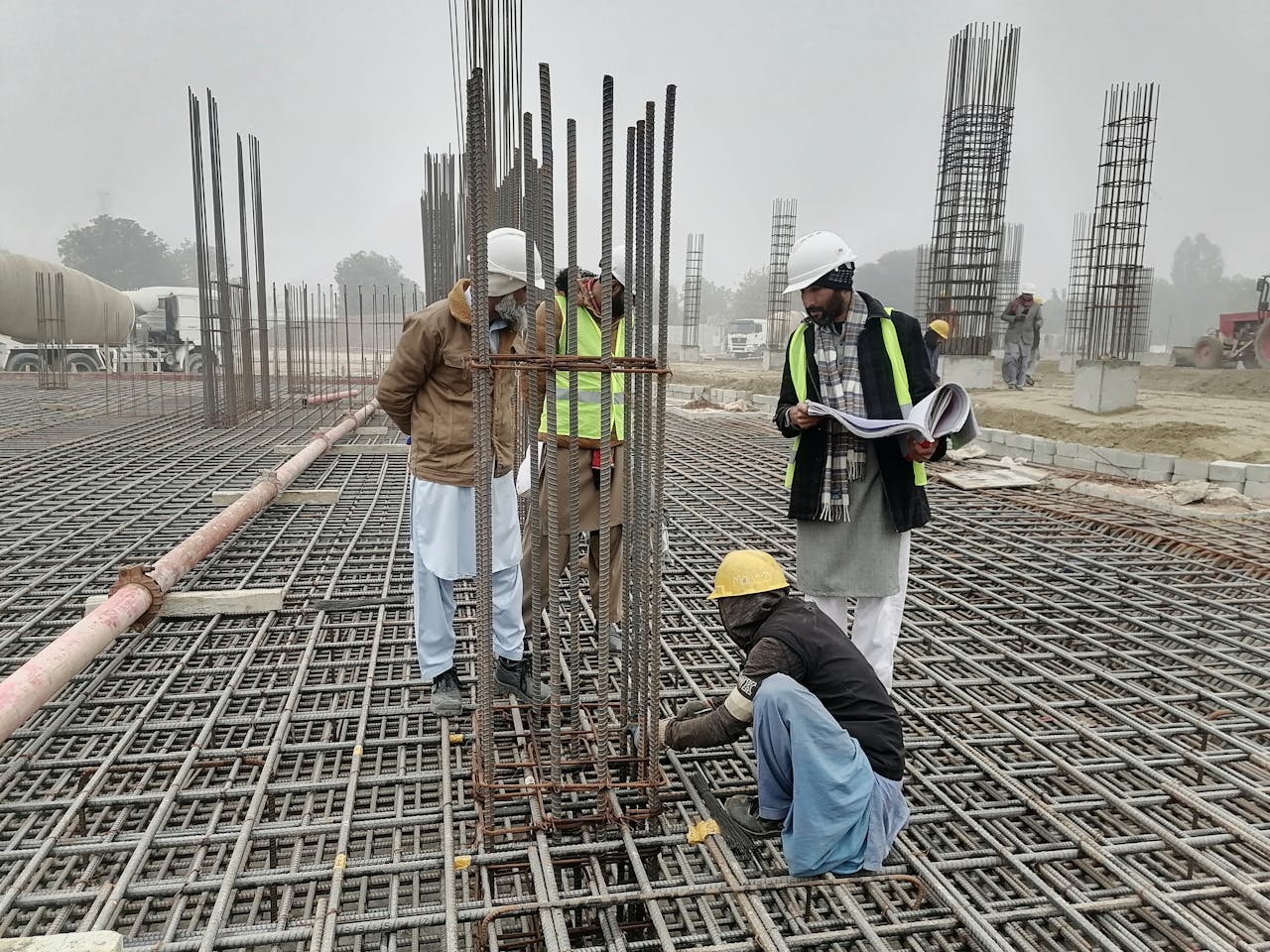 Construction workers and engineers at a site in Bahāwalnagar, Punjab, Pakistan, inspecting metal framework.