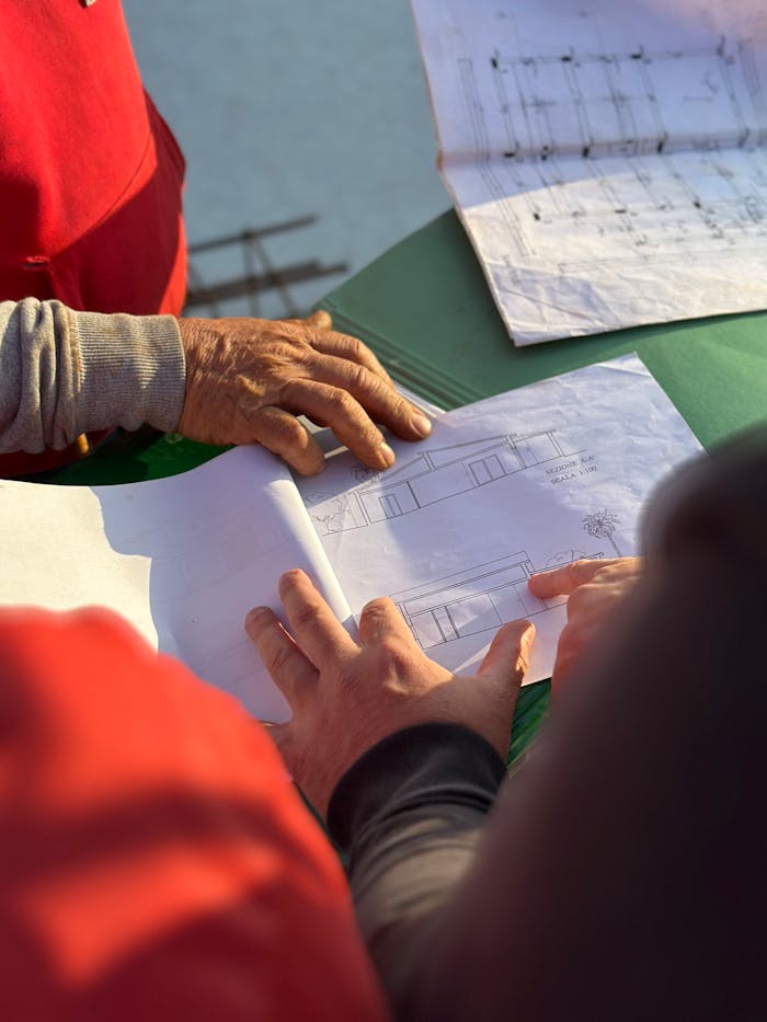 services-03 A team of architects examining architectural blueprints at an outdoor construction site.
