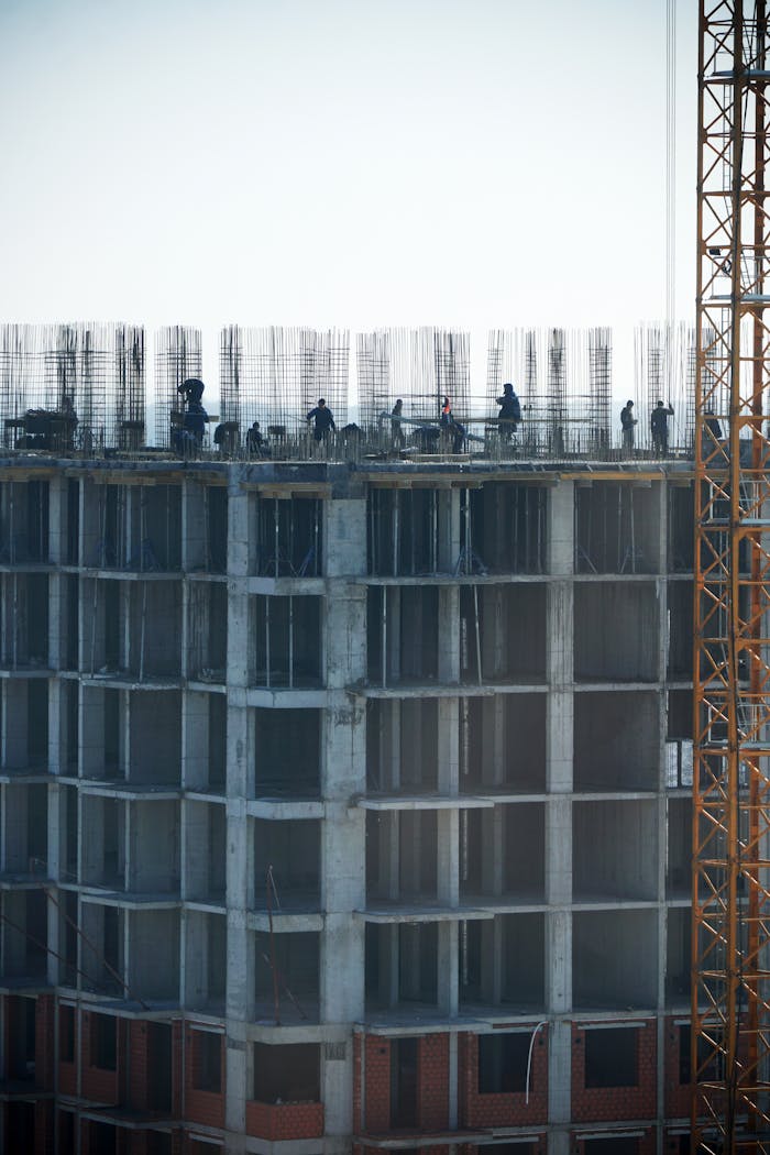 about-02 Construction workers building a high-rise, showcasing urban development.
