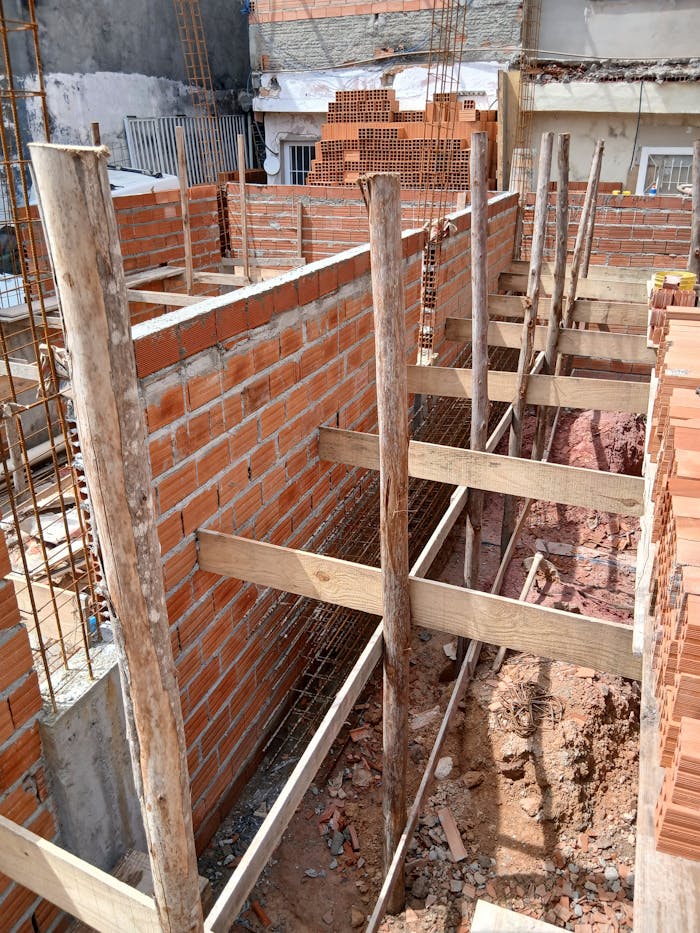 ours-journey Construction site with brick walls and wooden supports under daylight.