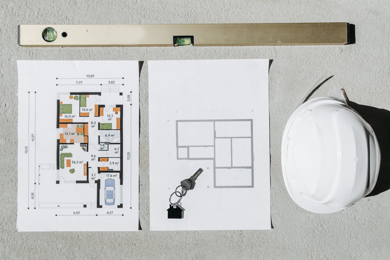 Blueprints, spirit level, and hard hat symbolize house planning.